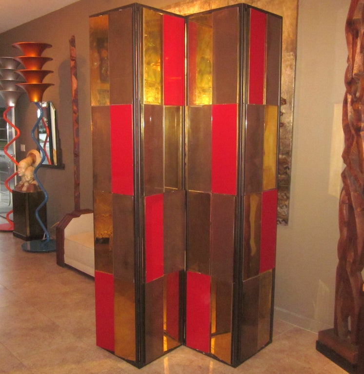 This incredible screen was designed for the Gucci Las Vegas store in the 1990's. The four interlocking sections feature revolving panels of various colors and materials. Each panel has a polished brass side, reversed with a dark bronze or red panel.