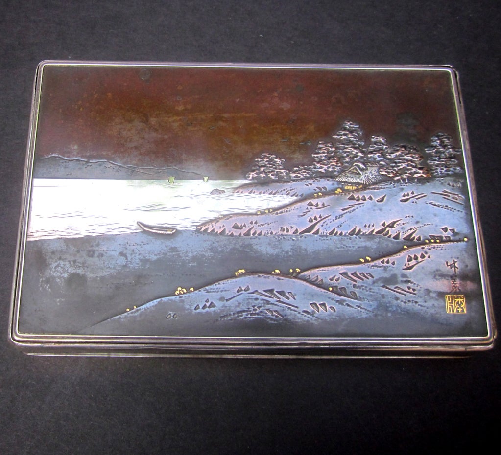 This lovely solid silver box is overlaid with bronze and copper scenery, and set in with a gold signature of the silversmith. The inside is lined with a dark rosewood, in very nice condition. The bottom of the silver box is marked with the Japanese