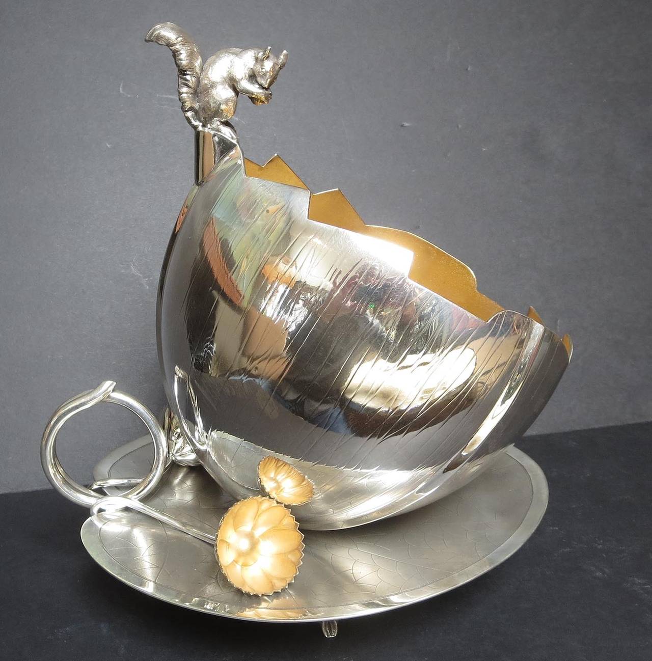 This lovely bowl depicts a small squirrel perched atop  a cracked acorn shell. The shell vessel sits atop a veined lily pad base, with a sensual pair of flowers decorating the edges. The silver plate is in remarkable condition, and the condition is