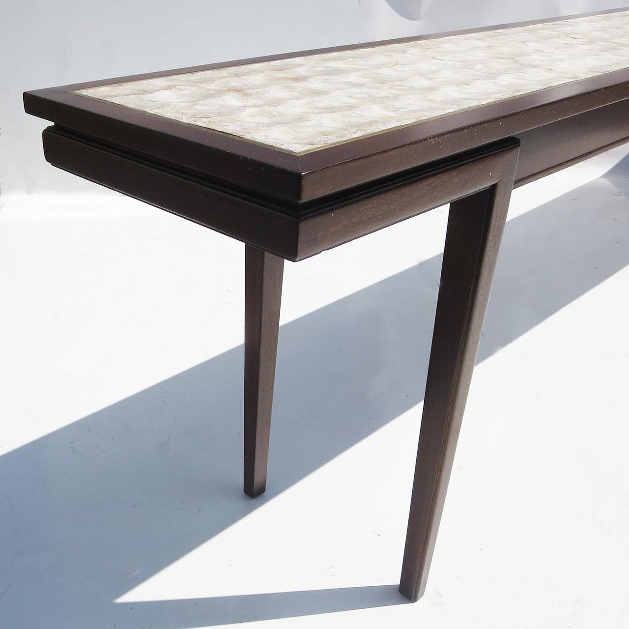 With a length measuring over ten feet long, this is certainly one of the more impressively scaled console tables we have ever seen! The form is stylish and modern, with very tasteful appointments and materials. The legs extend beyond the body,