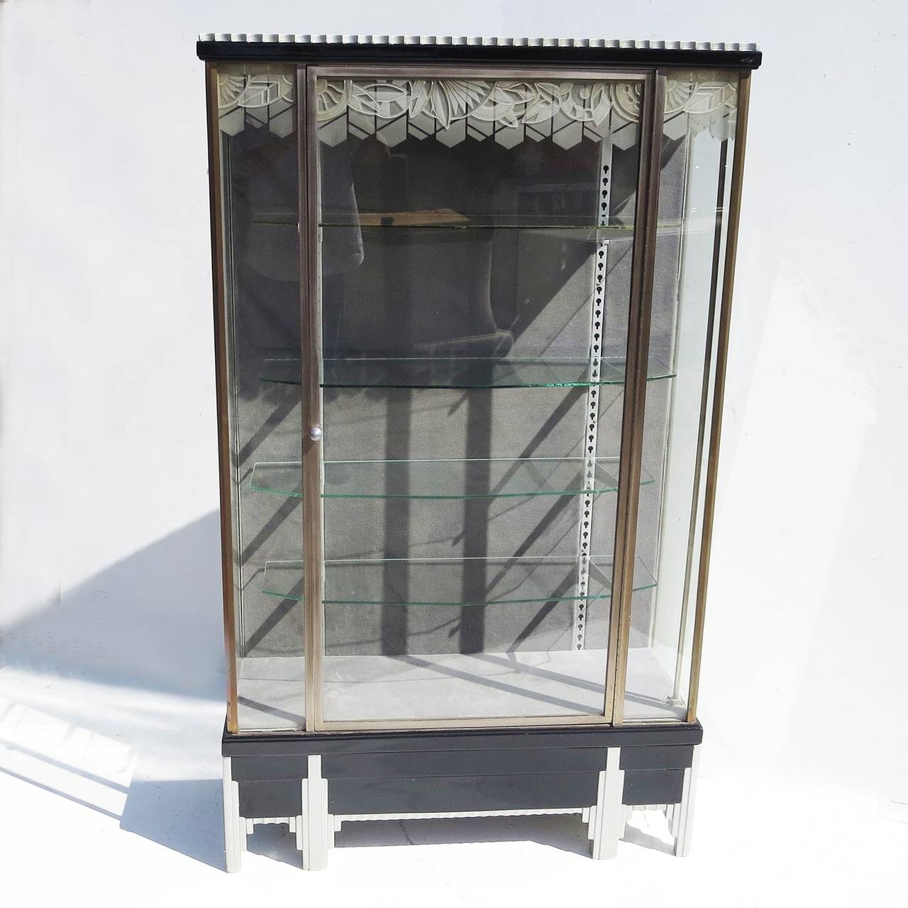 One of the best we have ever seen! The case is made of a combination of bronze, etched glass, and lacquered woods. The glass panels are carved in a geometric pattern on the outside, and frosted with a complimentary pattern on the inside. The base of
