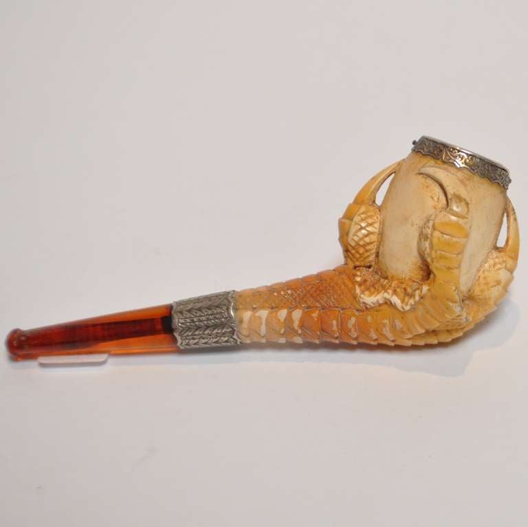 A lovely and ominous carved pipe depicting a eagle talon surrounding an egg. The small scale of the bowl suggests a pipe used for opium or hashish rather than the larger tobacco pipes. The bowl and stem are banded in tooled sterling silver and the