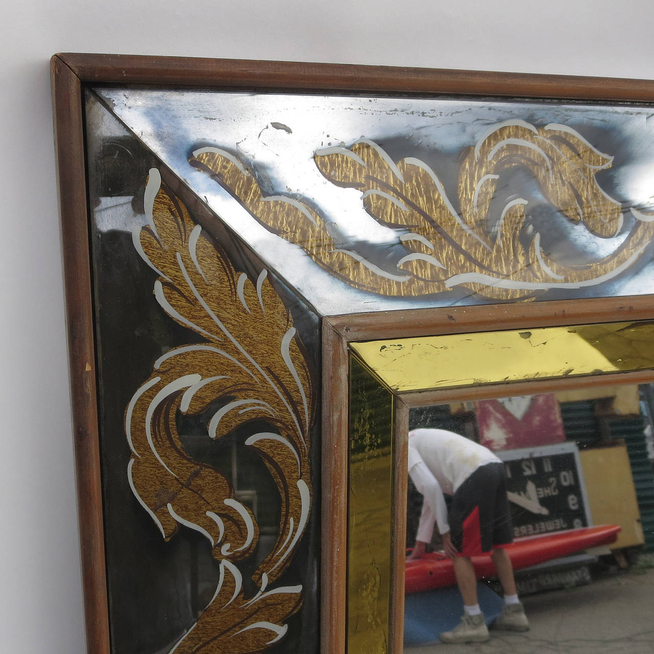 A wonderful decorative mirror in a spectacular scale! This large mirror is framed in panels of wide glass, reverse decorated in a golden fleur-de-lis pattern. The inner bevel of the wooden frame is a golden yellow mirror, intersected with faceted