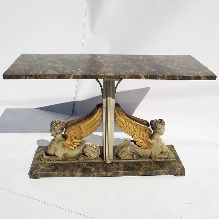 This lovely table , designed in the Neo Classical style, sports two winged mythical women, posed end to end. The table is all solid woods, and finished in a combination of faux marble, paint, and gold gilding. All finishes are original, and show a