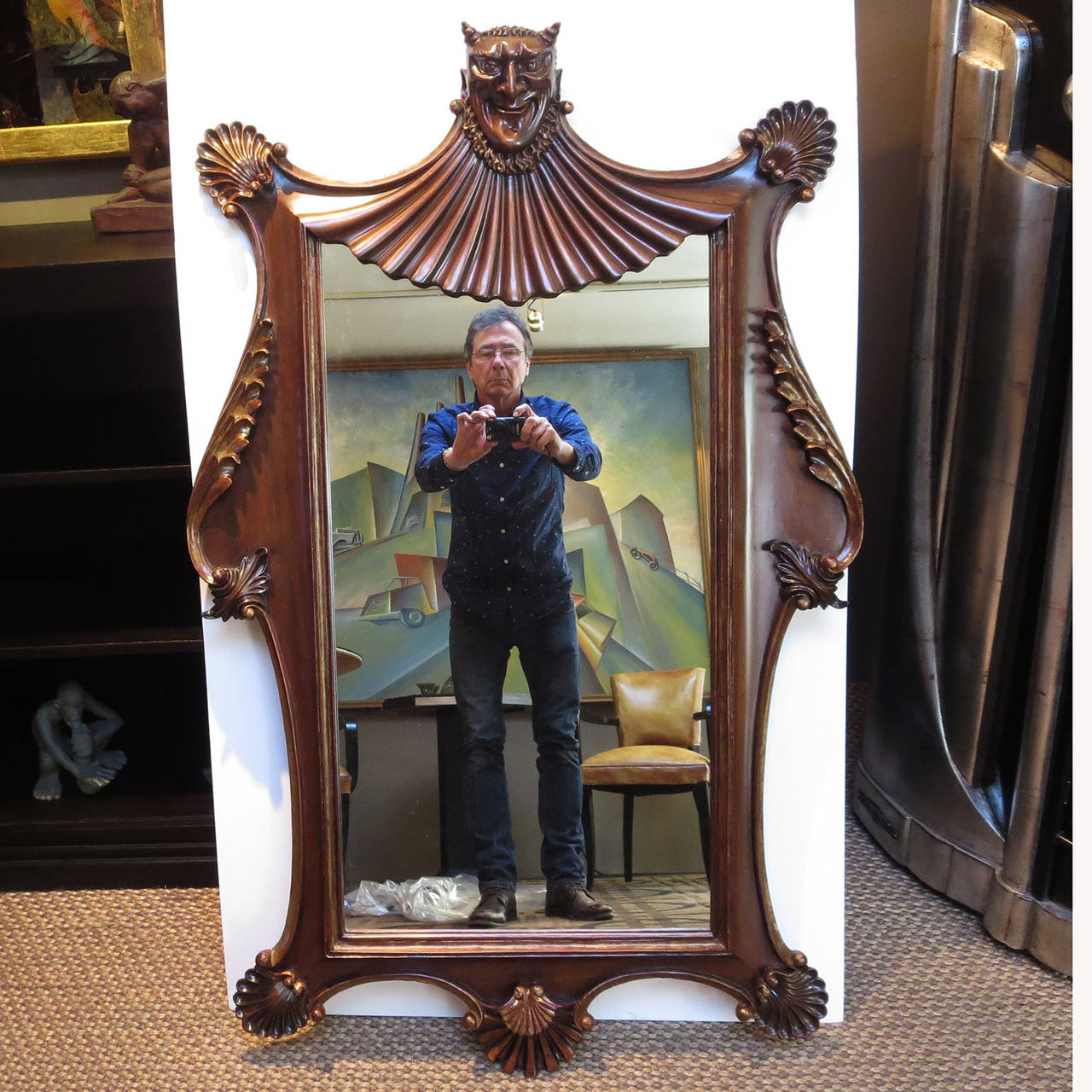 A wonderfully charming mirror in carved and finished mahogany, this devilish fellow will add spice to any décor. The carving is of the highest quality, and in fantastic condition. The mirror is clean and nice, as well. The back side shows quite a