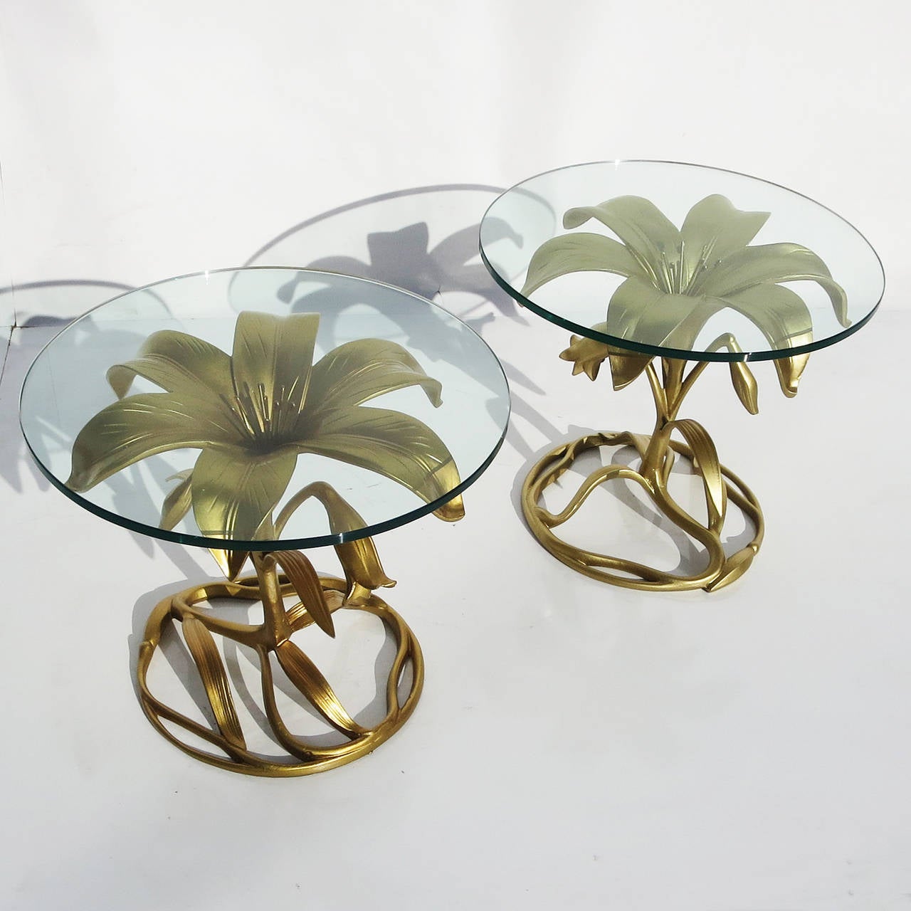 A lovely pair of golden lily tables by the master of aluminum, Arthur Court. The tables are in remarkable condition and almost appear new! The heavy polished glass tops have been replaced, so there are no scratches or issues. The tables are solid