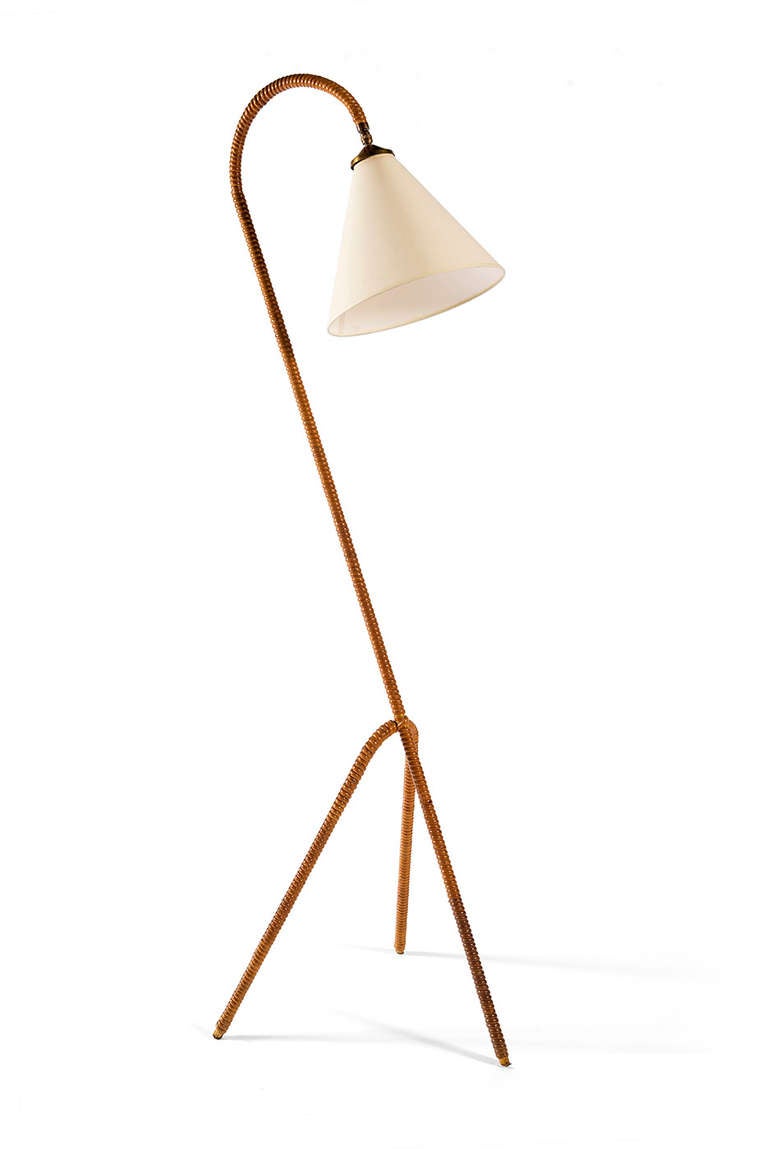 Rattan wrapped floor lamp on tripod base with adjustable cone shade.