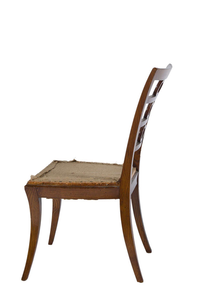 French oak dining chairs from the estate of Amy Perlin. Features three central rings on a ladder back with splayed legs.