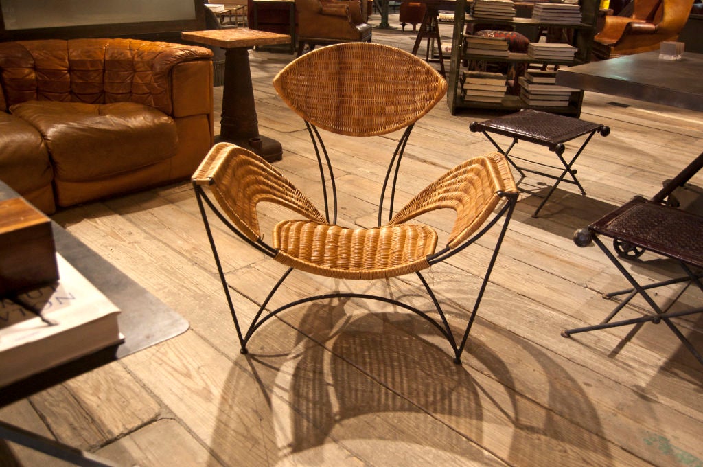 A very unusual wicker rattan swan-like side chair woven and supported by beautifully bent iron frame on bun feet. Eye shaped back rest with wing span arms and bowed seat.