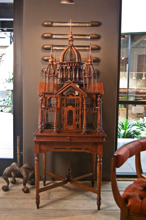 A rare birdcage from the Victorian Era, nice little bell on perch, outfited with doors on all four sides, hand crafted in mahogany and steel wire on stand with built in shelf, lathed wood detailing.