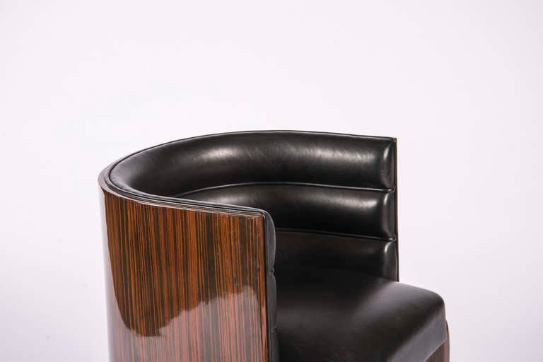 Macassar rounded seat back with channeled black leather upholstery on spayed legs.
