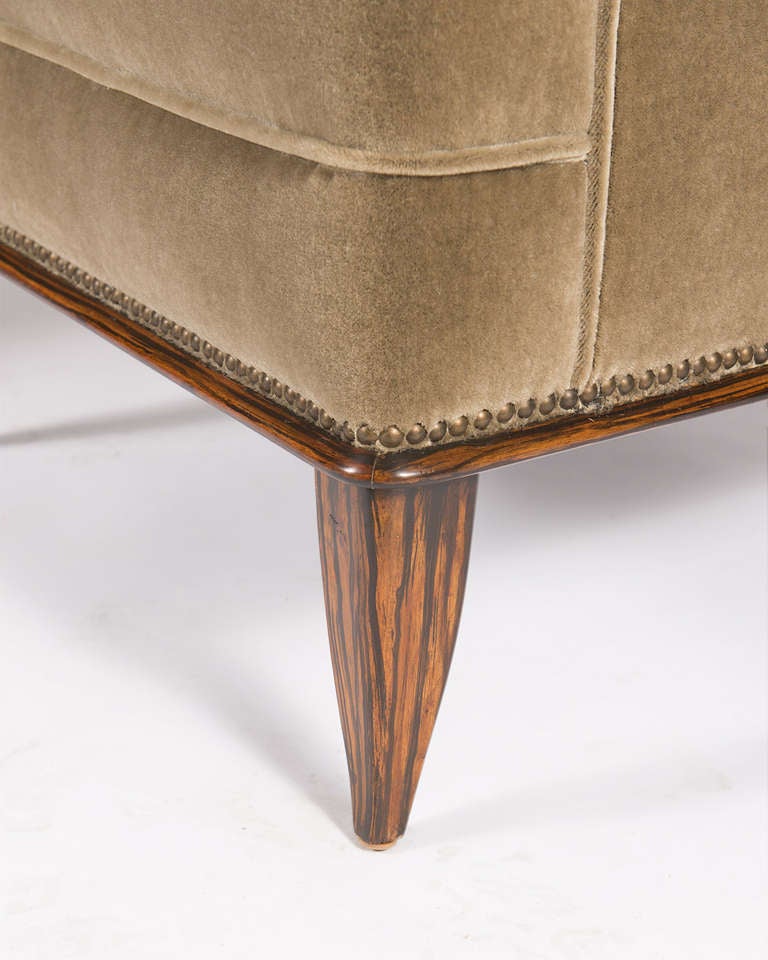 Pair of club chairs in the manner of Jean-Michel Frank. Splayed arms, nailhead trim on base, with faux Macassar, straight back legs, and splayed front legs.