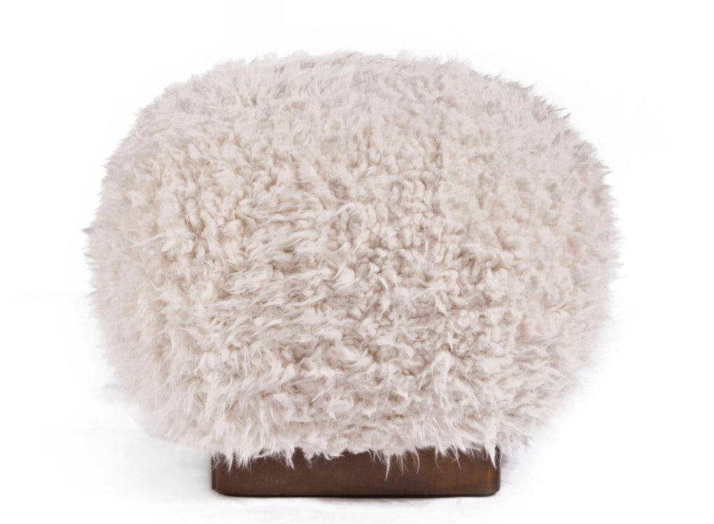 Wooden frame pouffe upholstered in faux fur with brass patina steel band.