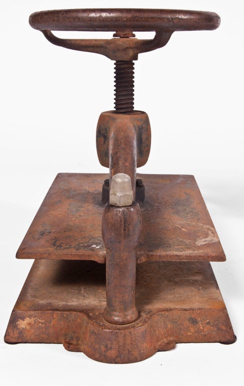 Rusted cast iron book press with turning wheel.