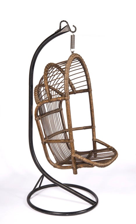 Hanging rattan chair on steel cantilevered base with stainless steel spring.
