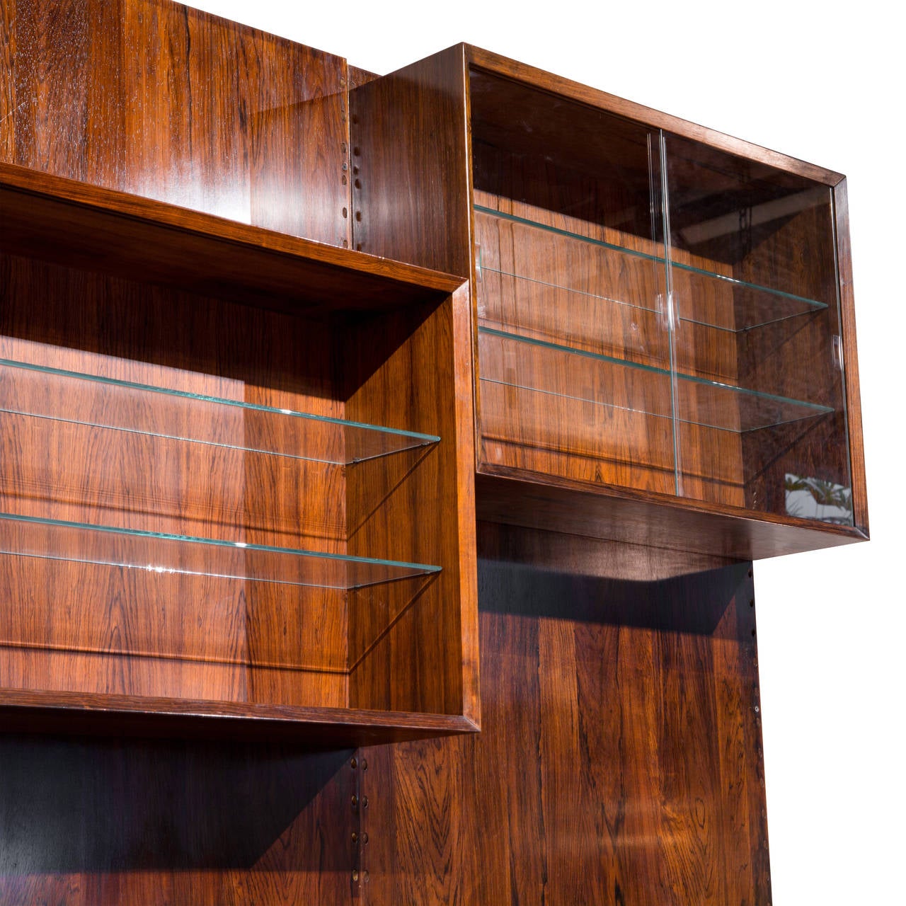 Stunning modular rosewood wall unit / bookcase by Poul Cadovius. Recently re-finished to bring out color and grain in wood. Four modular cubes with two glass shelves each. Wall mounted.