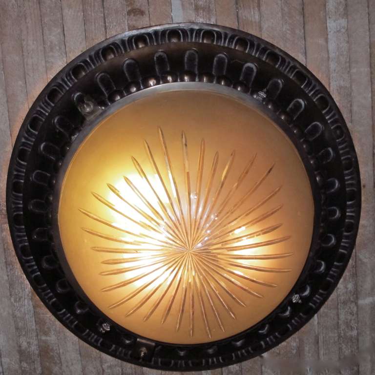 Large bronze flush mount ceiling light with egg and dart outer border and bead rim around the ivory frosted star burst cut glass shade.  American, Circa 1920.