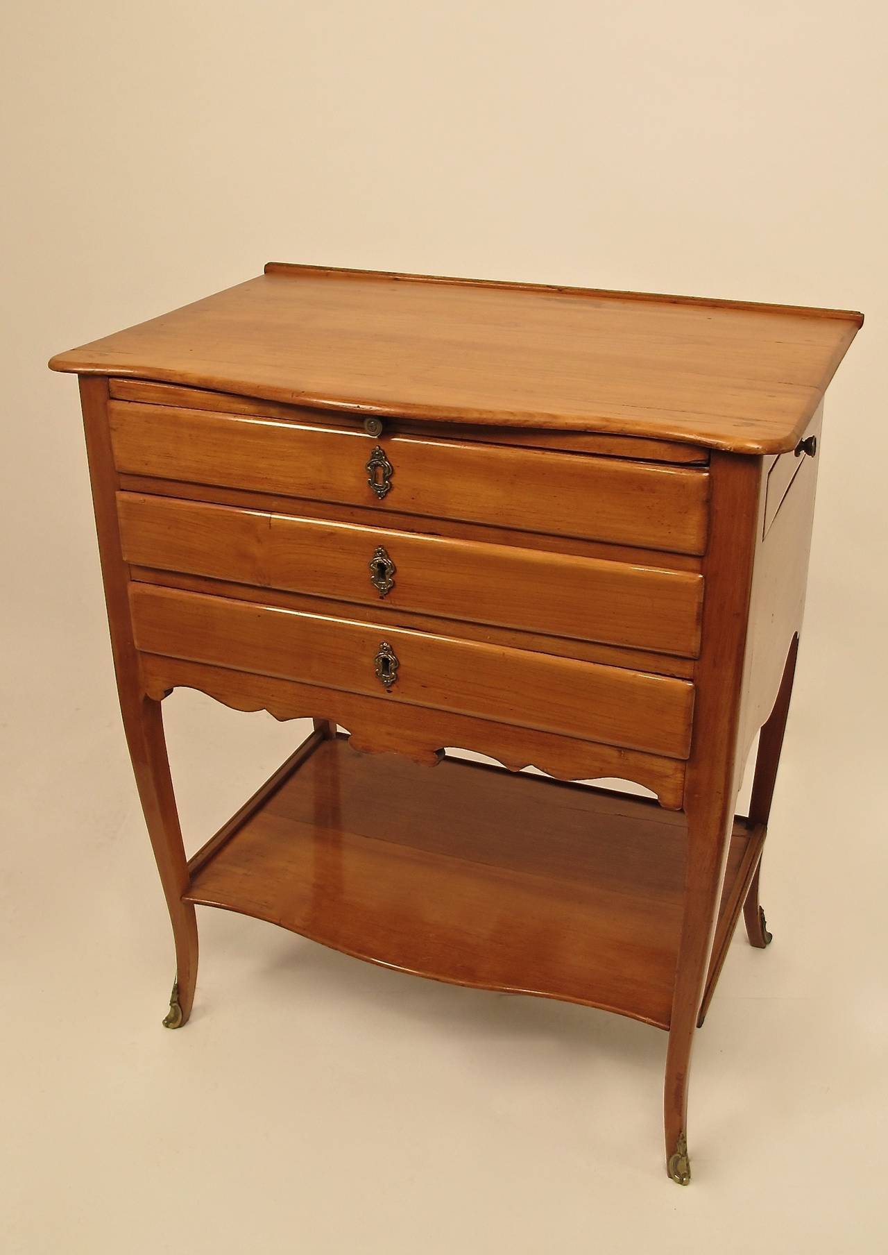 A French Provincial style cherrywood work or sewing side table, late 18th-early 19th century. Having a leather inset pull-out work surface, three front drawers, one side drawer, and a back pull up partition.