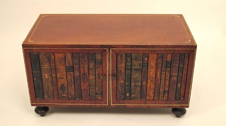 Leather coffee or low table with two door cabinet. All leather over wood with embossed gilt trim, and with genuine 19th century book spines on doors.