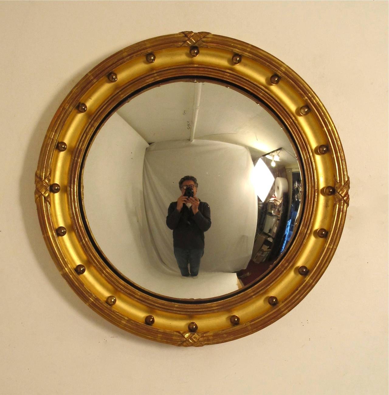 Carved wood and beautifully gilt English convex mirror with unusual solid brass balls detail. England, circa 1820.