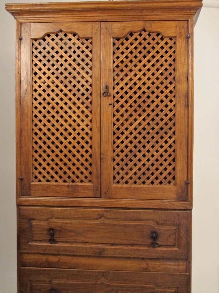 Handsome solid elmwood cabinet, having lattice front cabinet doors and three shelves (removable) over two lower drawers, circa 1825.