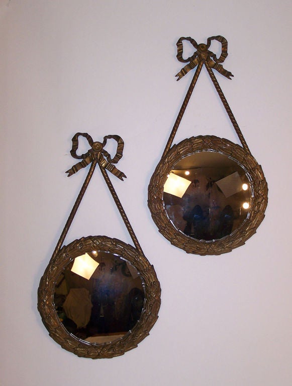 Pair of cast brass laurel wreath frames with fisheye or convex mirrors.