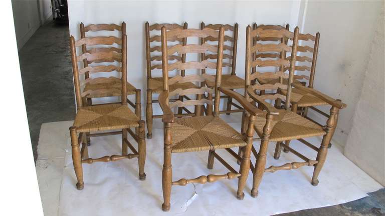 A complete matching set of 8 elmwood ladder back chairs (2 arm chairs and 6 side chairs). Currently stripped of their stain and finish and with new rush seats (we can color or stain if desired for an extra charge). On two chairs the front turned
