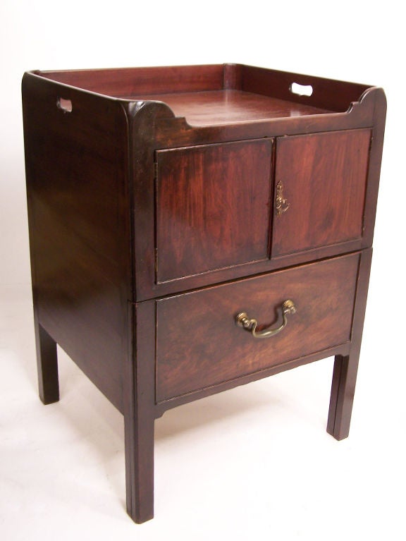 Mahogany Georgian bedside commode with wooden gallery around the top above pair of cabinet doors and a single slide out drawer, standing on canted legs. Brass pull and bale handle. English, circa 1830.
     