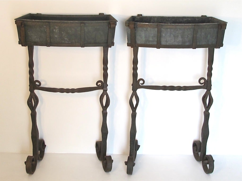 A pair of very nice looking and heavy wrought iron planters with original zinc liners.