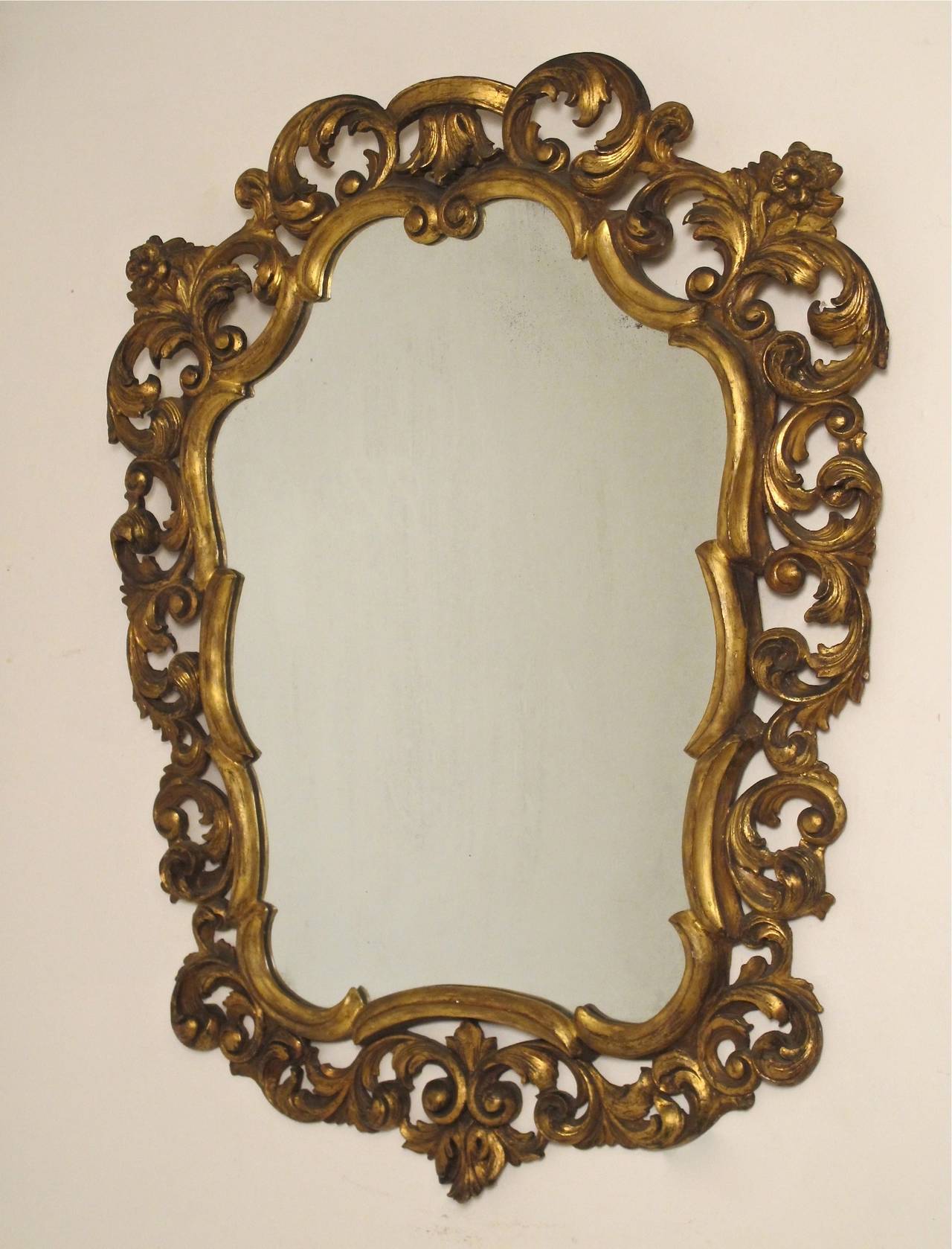 Shapely carved giltwood framed mirror by Fratelli Paoletti with C scroll and floral design. Italian, circa 1950.