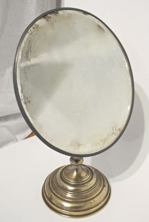 Antique nickel plated countertop mirror on weighted base. Oval shaped beveled edge mirror, shows some age and minor clouding.