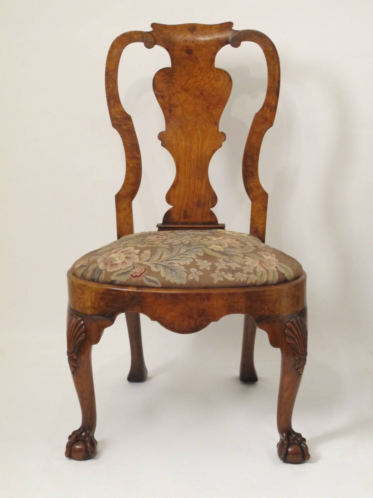 A finely crafted walnut and burled walnut side chair with shell carving on the knees ending in detailed claw and ball feet.