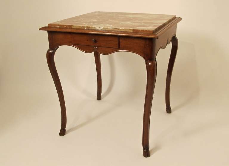 French side table with inset marble top, single drawer and scalloped apron. The slender and graceful legs tapering down to a cloven hoof. Marble top possibly replaced.