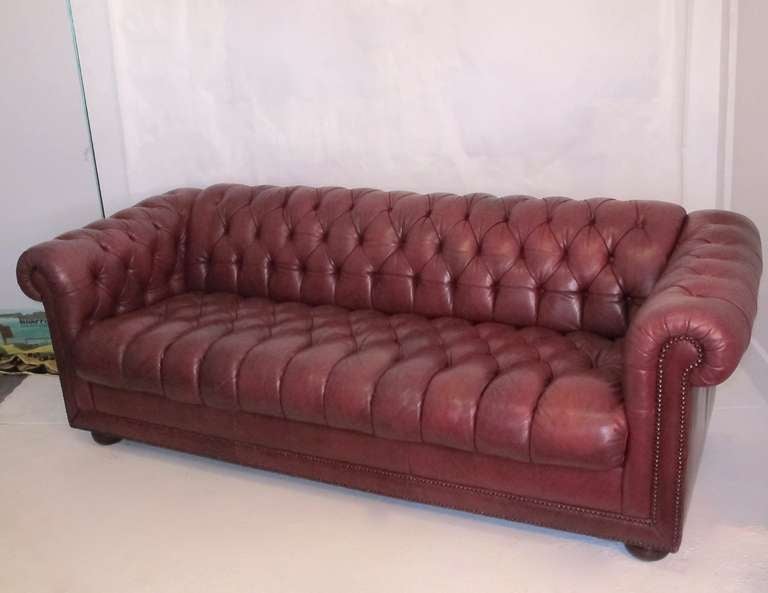 English style chesterfield or sofa with bun feet and nailhead trim detail. Beautifully aged and faded red cordovan red leather.