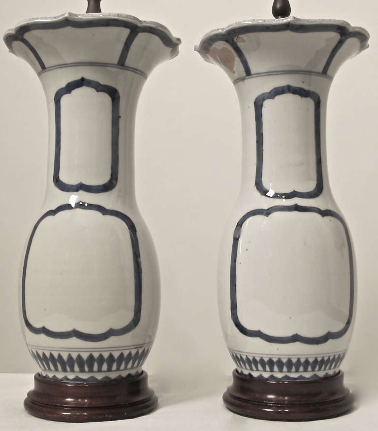 Pair of Chinese Blue and White Porcelain Vase Lamps with custom wood caps and bases. Unusual hand painted blue lined cartouches on front and back of each vase.  With Brass fittings and double sockets on each lamp.  Vases are 19th. Century, Wiring is