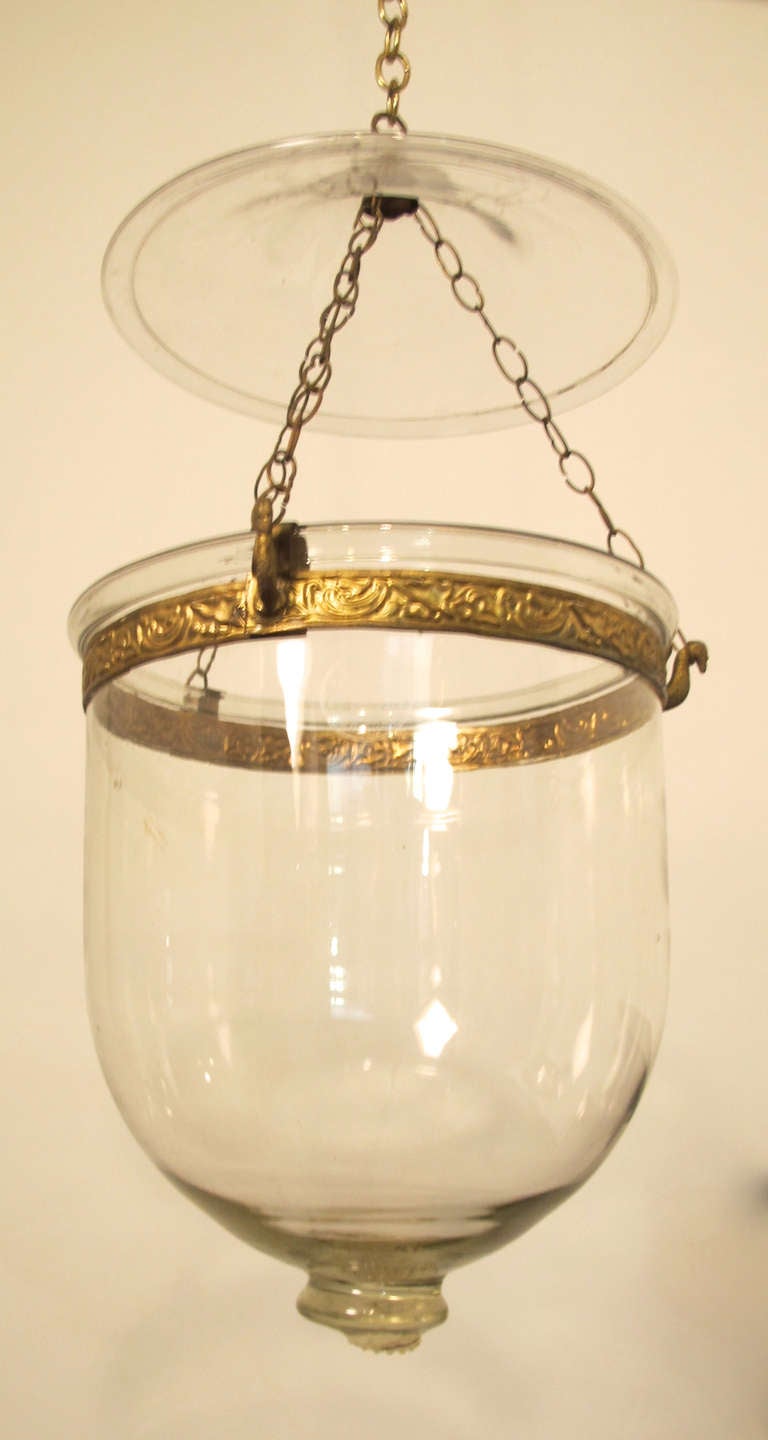 Original glass hurricane lamp with decorative brass hanger and chain.  Glass is free blown and attractive on its own. It appears to be European, probably Dutch. The full height (to top of canopy) as shown is approximately 18 inches. The diameter is