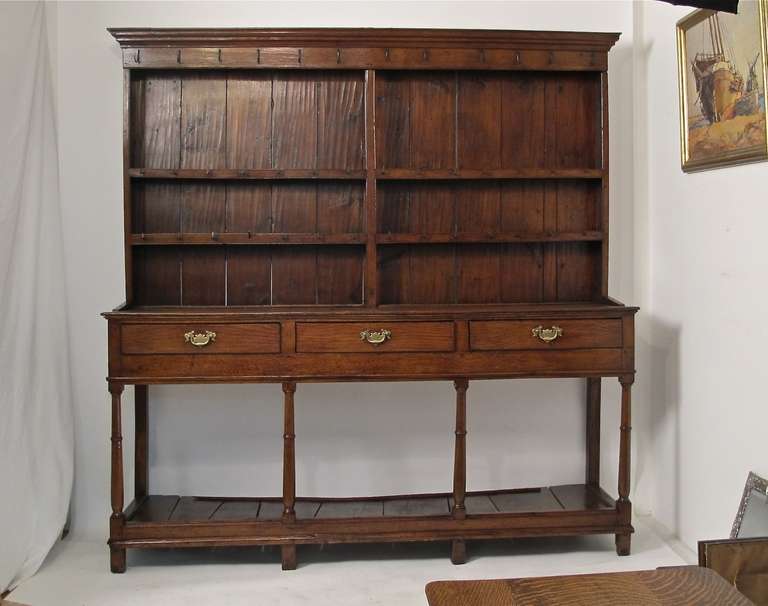 Genuine George II English or Welsh oak dresser in original condition with original iron hooks for mugs and tankards. Recently repolished.

Could be used as a buffet or server if the plate rack and cleats were removed.