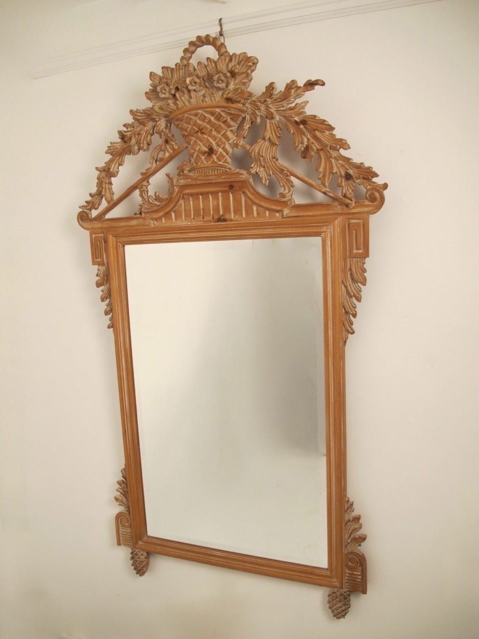 Cadre en pin finement sculpté à la main avec miroir en verre biseauté et finition blanchie à la chaux. Le centre est surmonté d'un panier de fleurs, des feuilles d'acanthe en volute drapant les deux côtés et flanquées de blocs de clés grecques, et