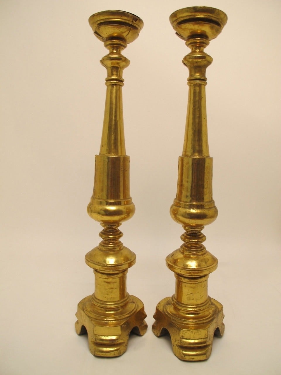 A robust pair of carved and gilt candlesticks with turned baluster shape columns sitting on trefoil bases and with scrolled feet. Italian, 19th century.