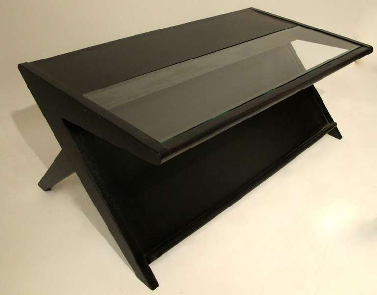 Ebonized black coffee table with inset glass top above lower shelf for magazines with X legs. Modernist, Mid Century made of oak.  American, Circa 1950's.