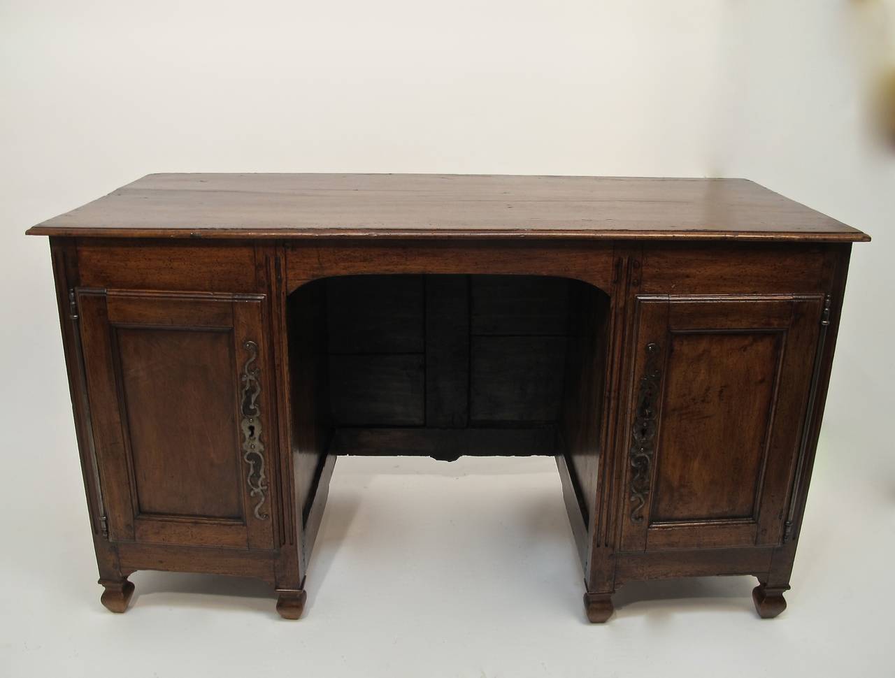 Beautiful deep patina to the walnut on this 18th century French desk. Side doors with original hardware open to two interior drawers on either side. Knee hole measures 26