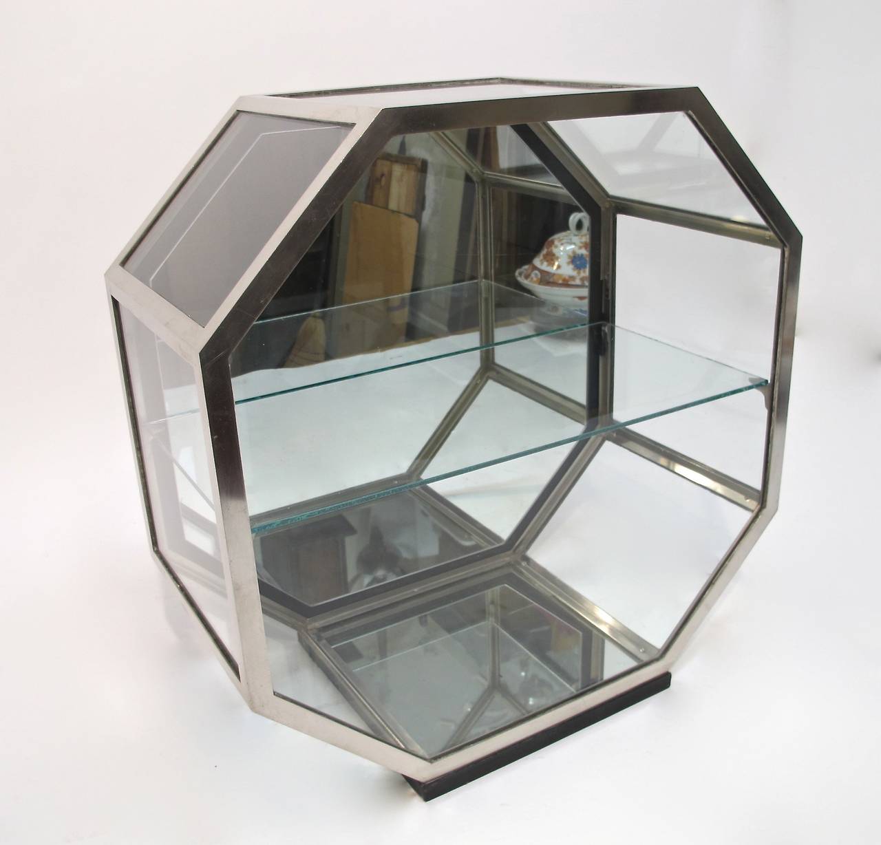 A quality octagonal shaped Art Deco period counter top display case. Nickel plated brass frame with a single shelf, and mirrored bottom and back. Case is in good original condition, it has one very small corner crack on the top glass section. Marked