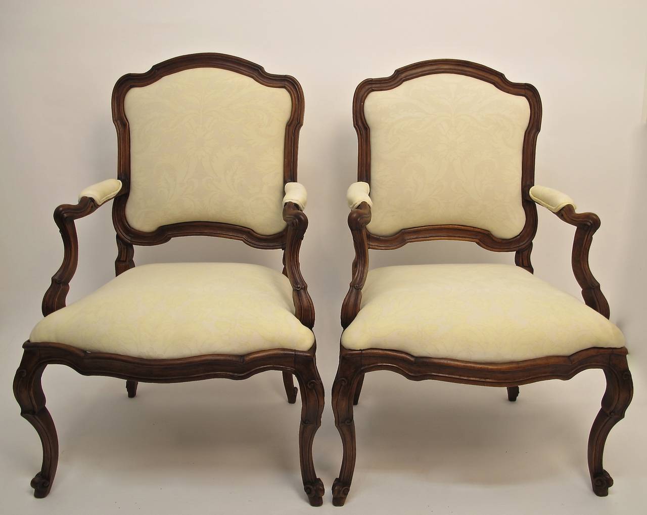 A pair of hand-carved walnut armchairs, recently refinished and newly upholstered with Fortuny fabric. Chairs are sturdy and sound with a generous size seat. Italy, Rococo period, circa 1780.