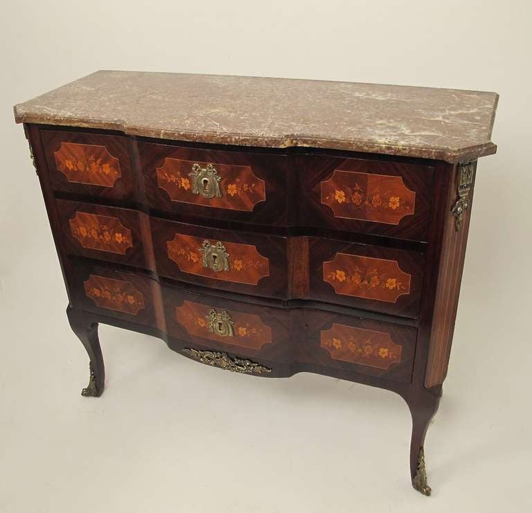 Unusual and elegant three drawer chest. Beautiful inlaid marquetry with original brass hardware hardware and sabots and bevelled edge rouge marble top. French, circa 1900.