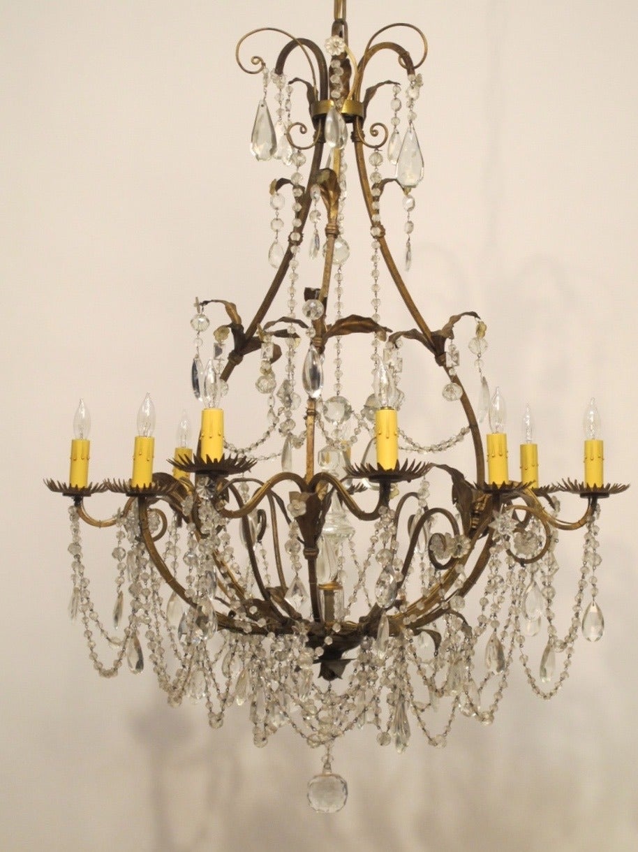Beautiful pear shaped gilt wrought iron chandelier with nine lights, crystal and glass pendants and swags with glass center finial. Excellent example of an early Italian light fixture, recently re-wired and some newer early 20th century prisms