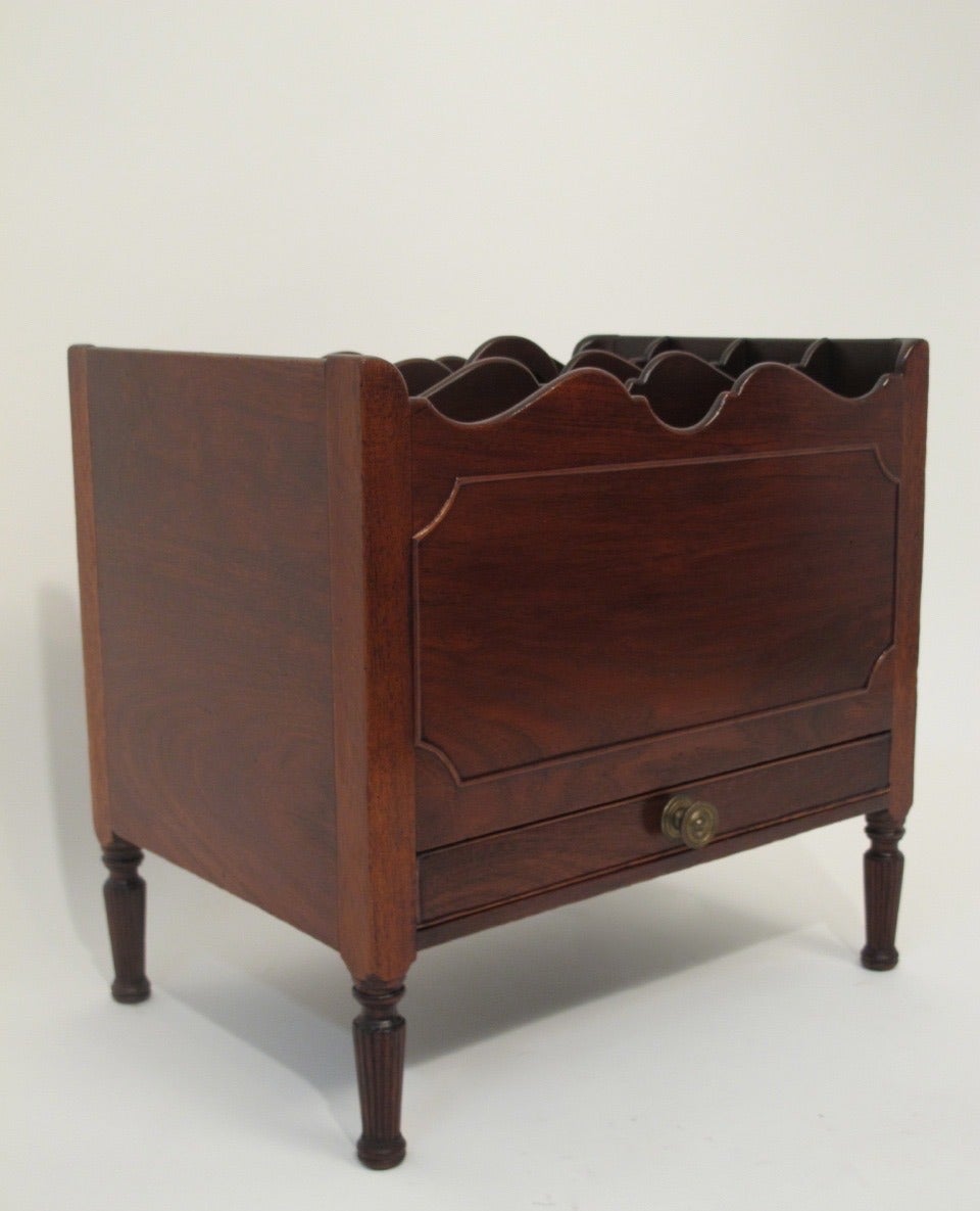 Mahogany canterbury with four sections above a single drawer, sitting on reeded turned legs. English, early 19th century.