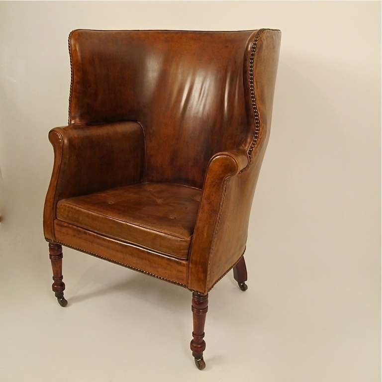 A very comfortable leather wing chair with beautifully aged original leather upholstery and porcelain casters. A typical style of a gentleman's club or library. England, mid 19th century.