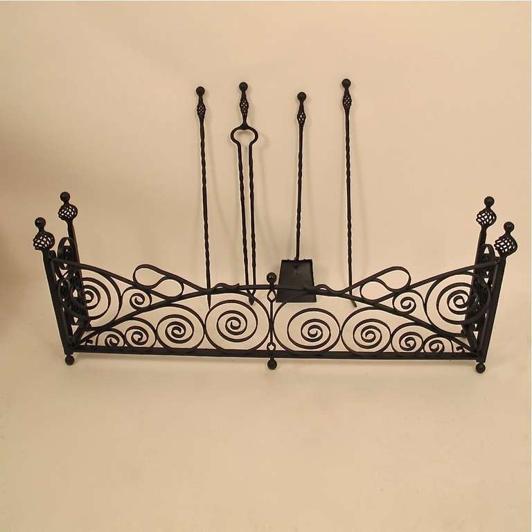 Arts & Crafts period wrought iron fireplace fender with four tools. Solid wrought iron, with painted matte black finish, American, early 20th century.