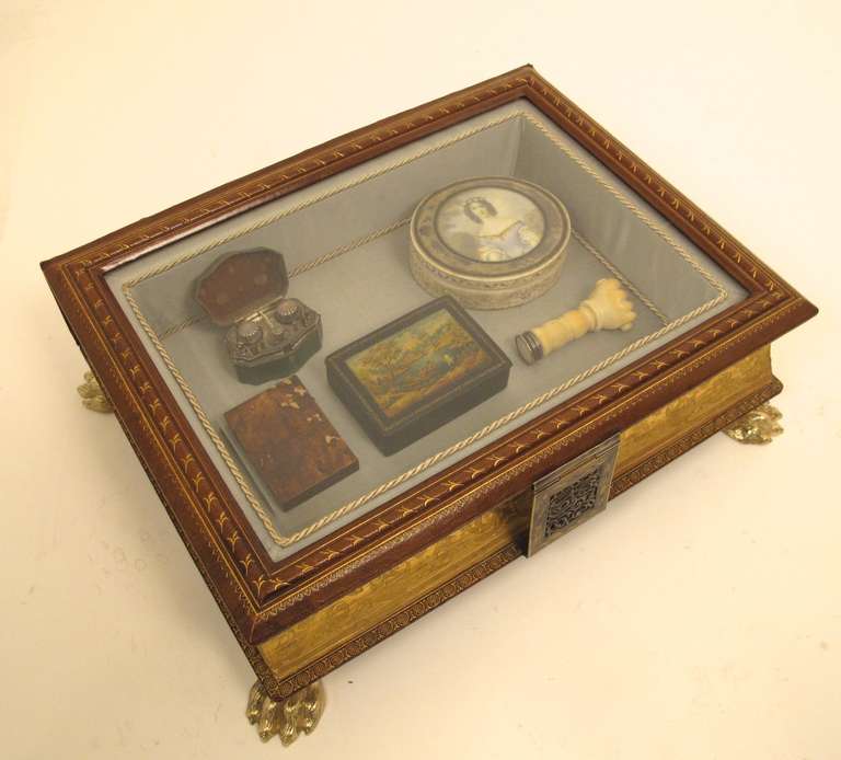 Exquisitely made vitrine made from a19th century leather bound   book.  Pages are compressed and handsomely gilded and the box closes with an impressive silver and gold clasp.  The top is beveled glass set into leather. Inside, a single compartment