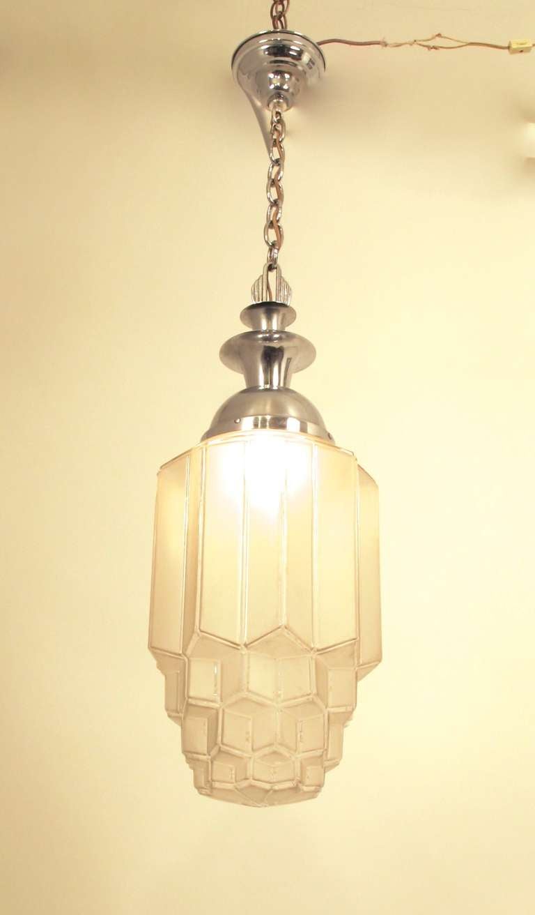 This genuine art deco hanging ceiling lamp was made in America, in the 20s-30s, of chrome plated steel. It has its original frosted shade; the chrome plating shows some pitting, consistent with its age.  The shade itself is 27